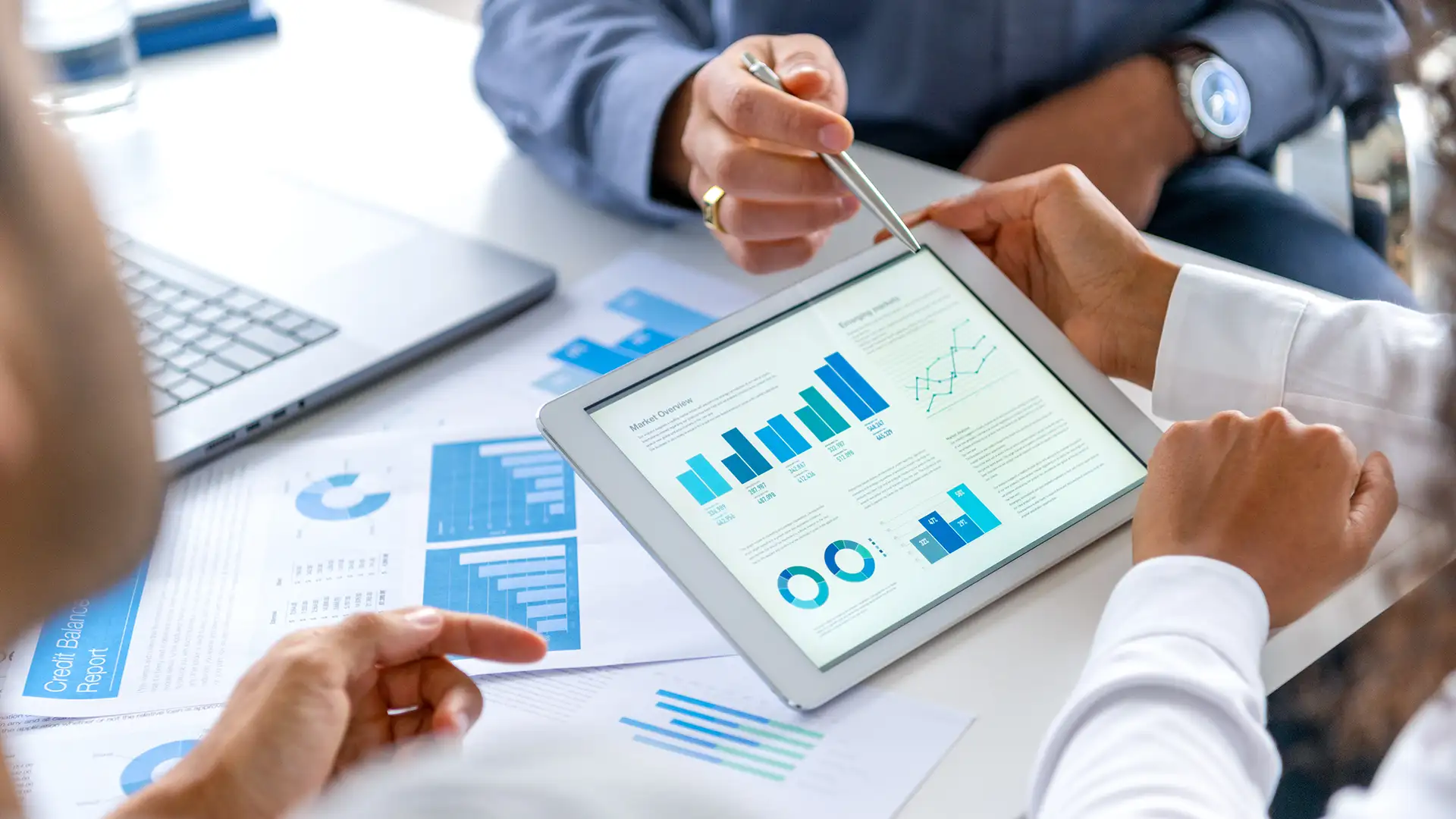 Professionnels en réunion analysant des graphiques financiers pour planifier un accompagnement stratégique.